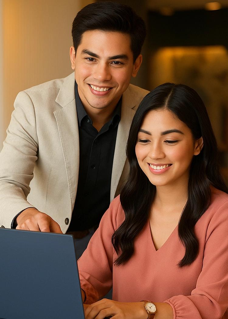 Two colleagues collaborating at a laptop in a warm, well-lit office space with modern decor and natural tones.