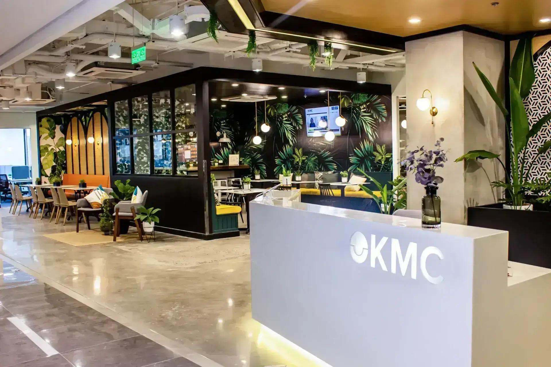 An office space in Armstrong, Makati with a sleek white reception desk, vibrant greenery, and a café-style workspace.