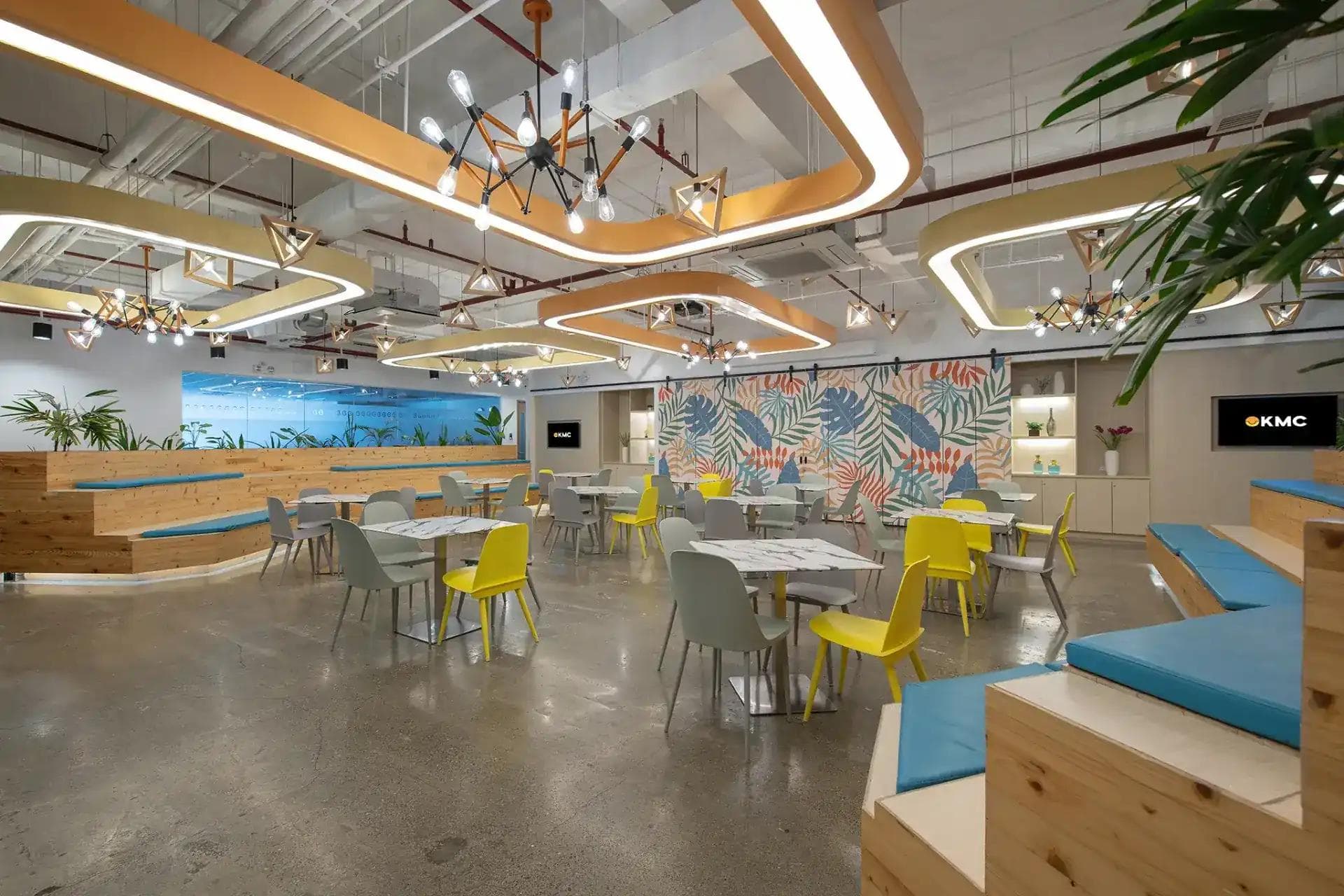 A vibrant office space in Skyrise 4B, Cebu with modern lighting, lush decor, white chairs and blue bench seating.