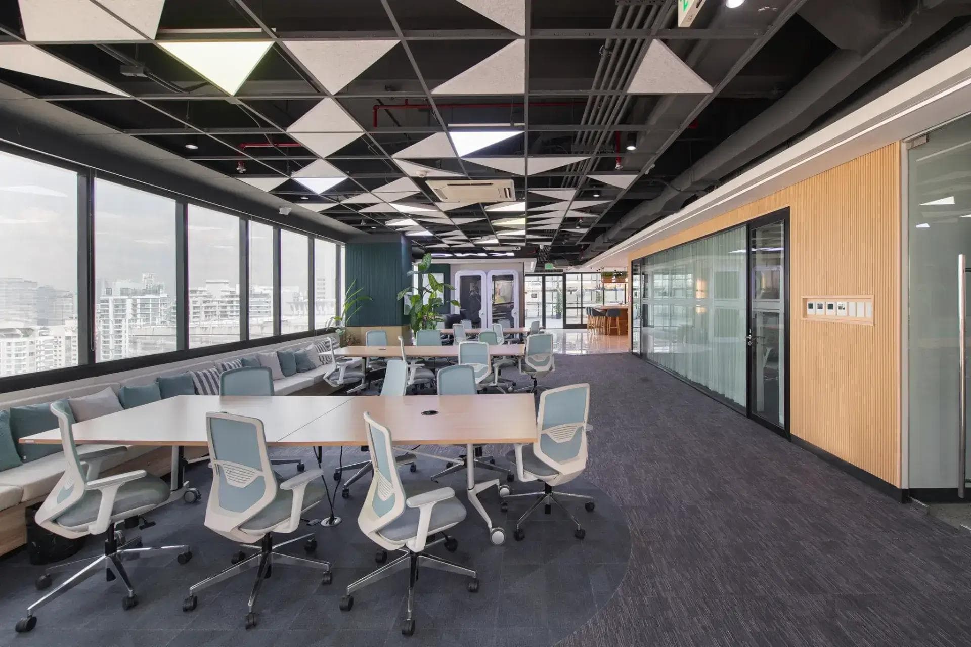 Spacious coworking area in BGC with modern chairs, panoramic city views, geometric ceiling, and a built-in lounge bench.