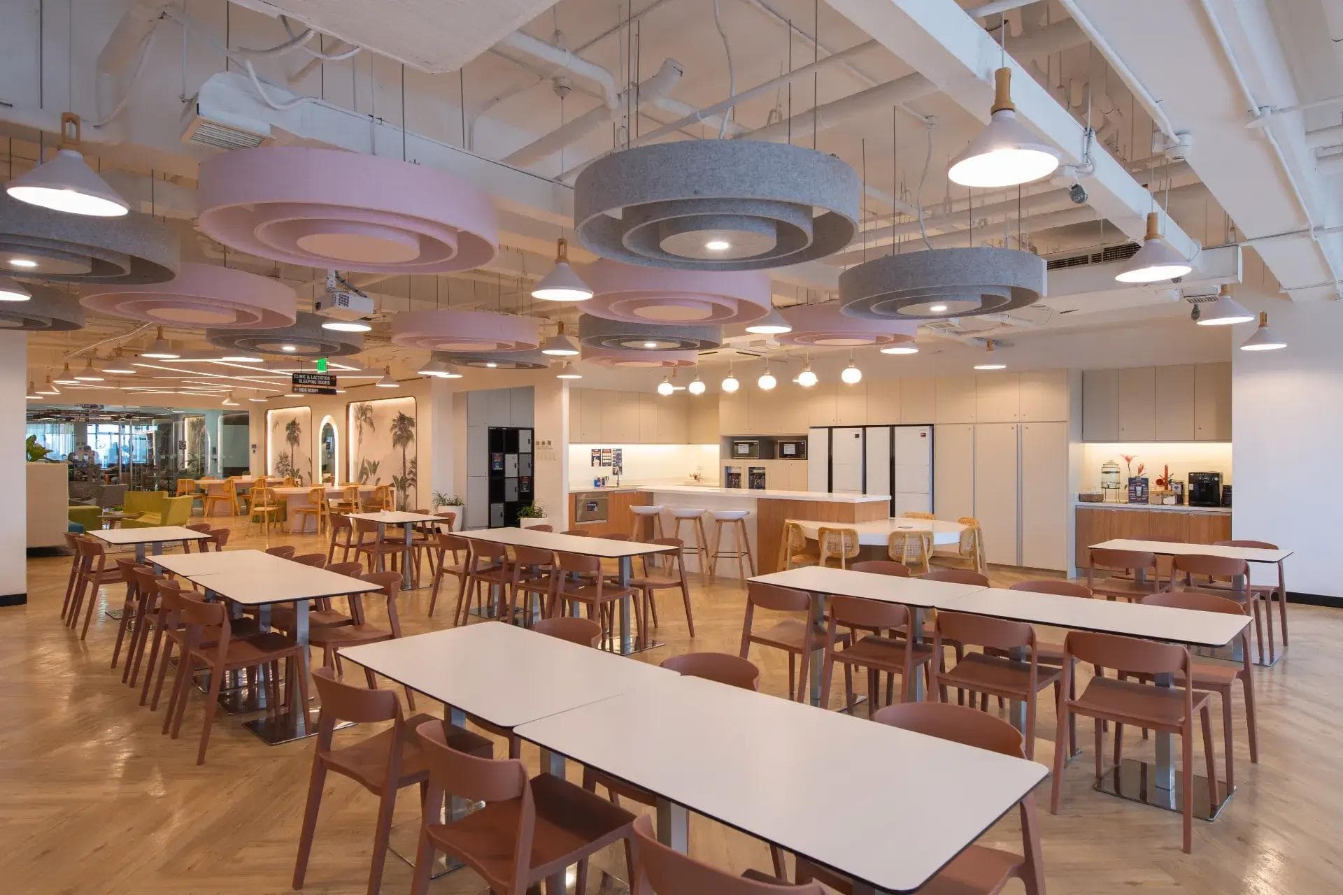 Office pantry at Cybersigma, BGC - with white tables, brown chairs, pastel ceiling accents, and a fully equipped kitchen.